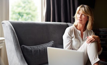 Mature Woman Using Laptop on Sofa